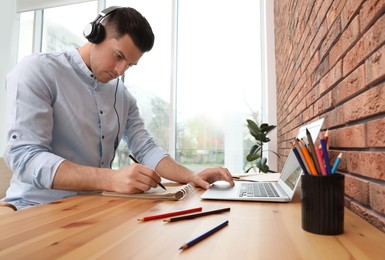 Photo of Man drawing in notebook at online lesson indoors. Distance learning