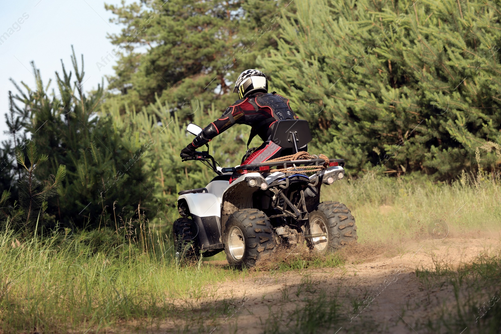 Photo of Man driving modern quad bike on sandy road near forest. Extreme sport