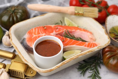 Photo of Fresh marinade, fish, lime, rosemary in baking dish and other products on table, closeup