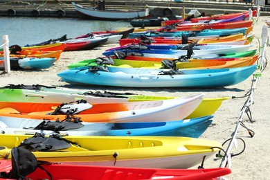 Photo of Many colorful kayaks on sand near sea