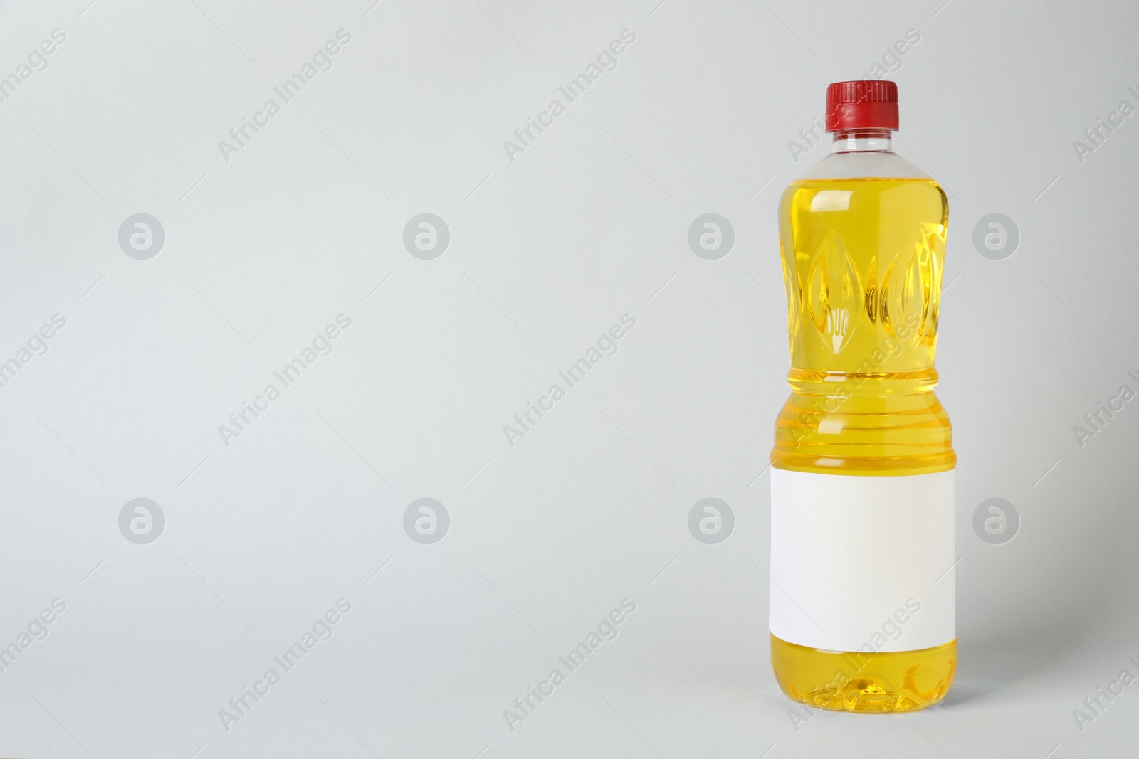 Photo of Bottle of cooking oil on light grey background. Space for text