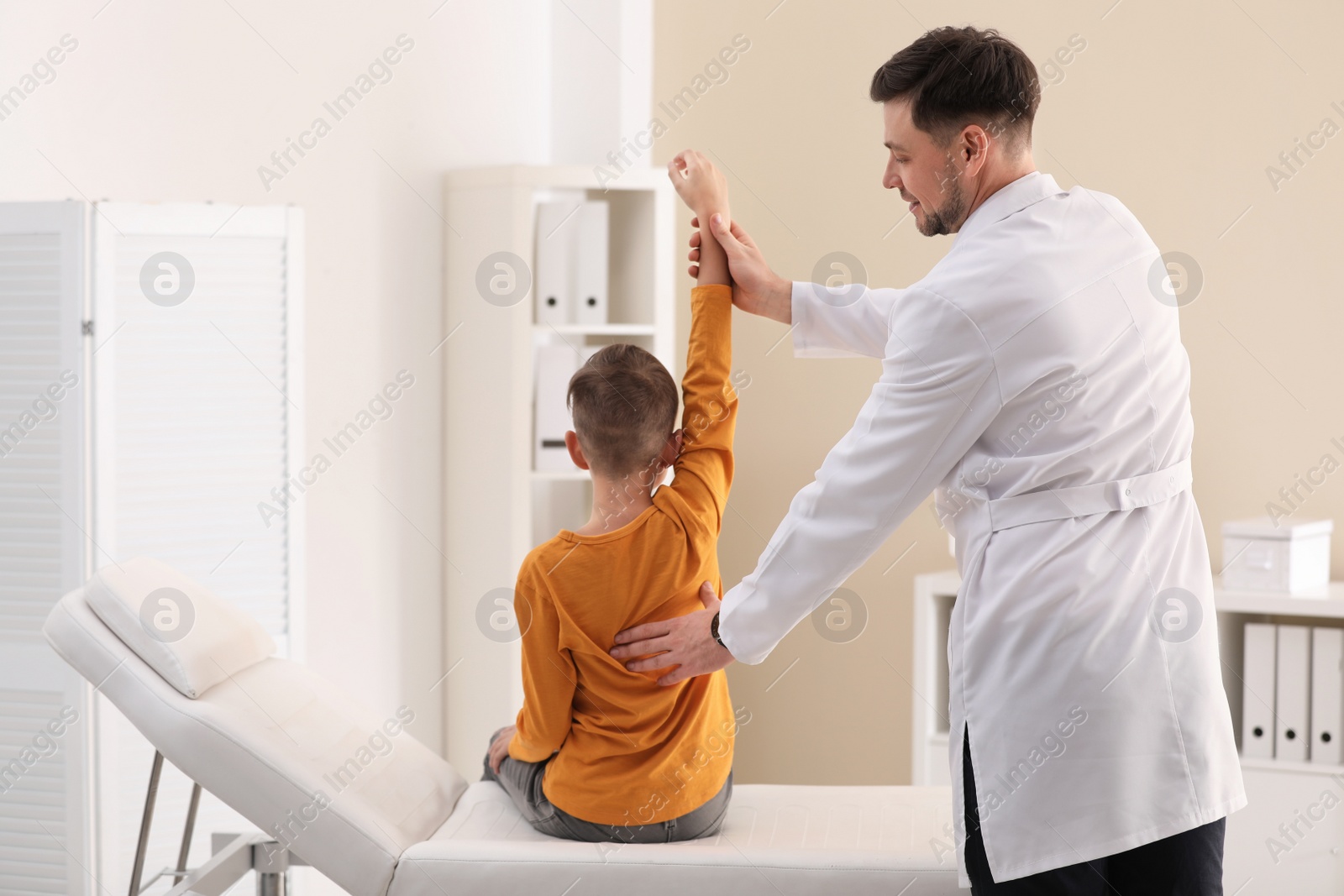 Photo of Chiropractor examining child with back pain in clinic