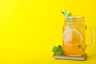 Photo of Delicious iced tea with lemon and mint on yellow background. Space for text