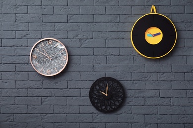 Different clocks on brick wall. Time concept