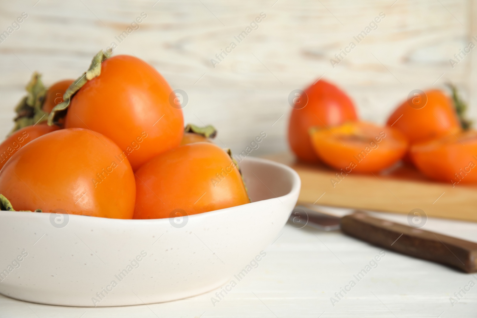 Photo of Delicious fresh persimmons on white table, closeup