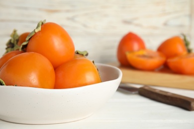 Photo of Delicious fresh persimmons on white table, closeup