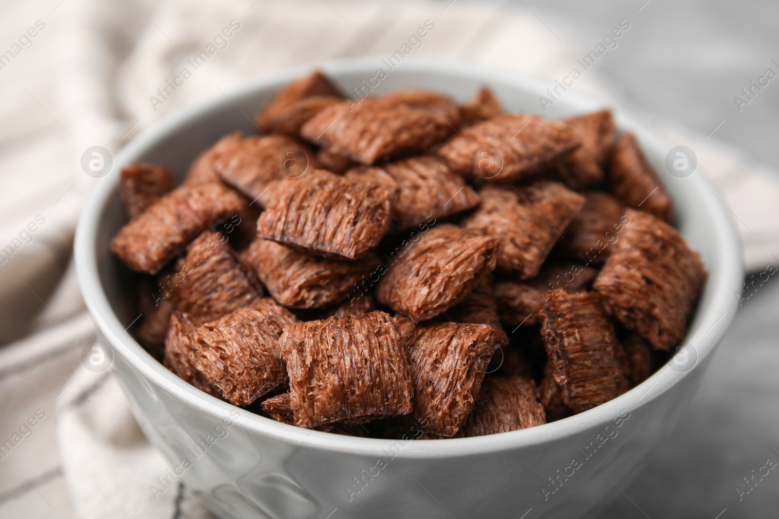 Photo of Chocolate cereal pads in bowl on table, closeup