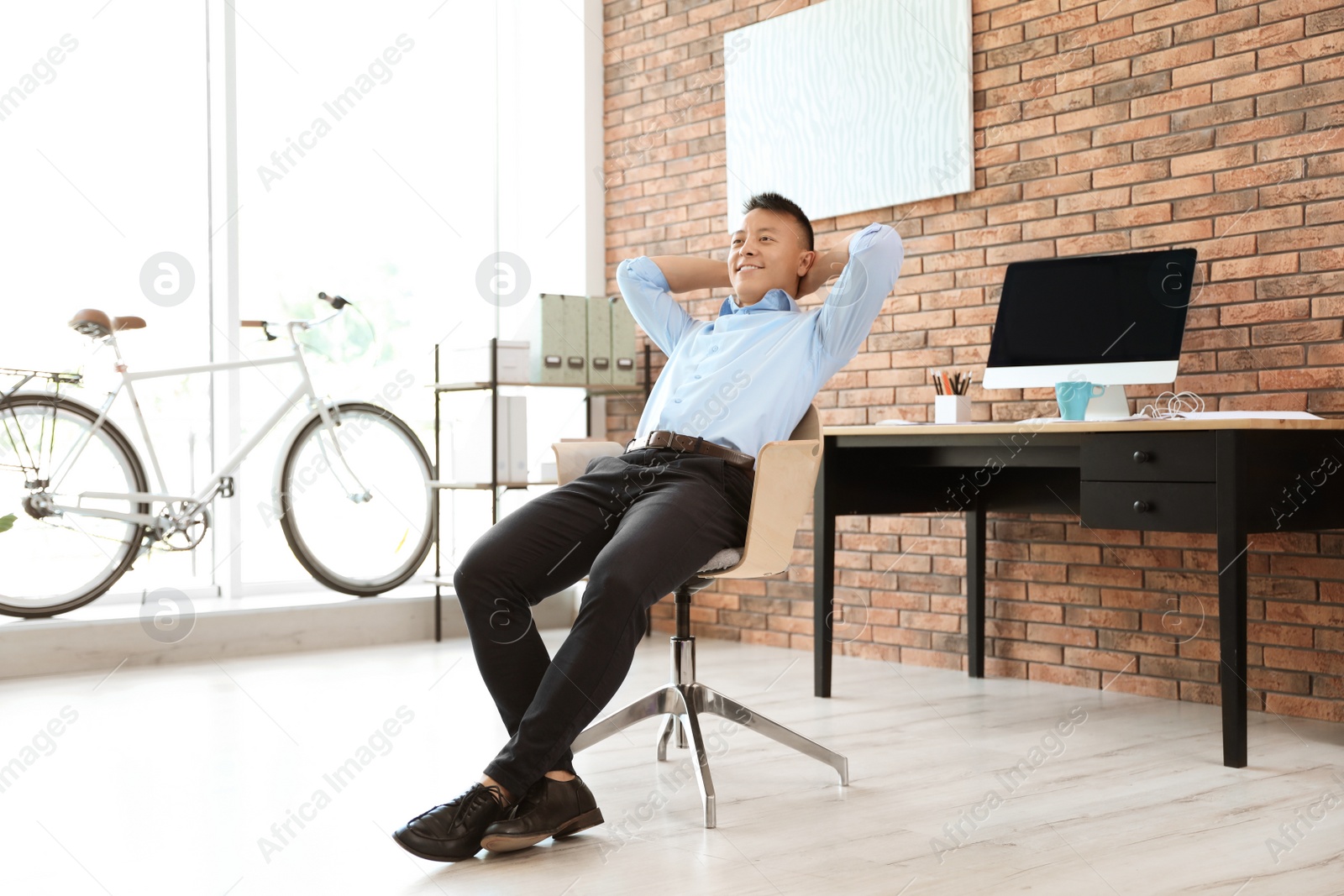 Photo of Happy young businessman relaxing in office. Enjoying peaceful moment