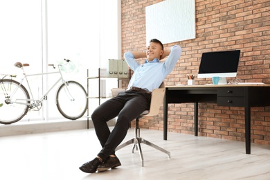 Photo of Happy young businessman relaxing in office. Enjoying peaceful moment