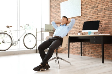 Happy young businessman relaxing in office. Enjoying peaceful moment