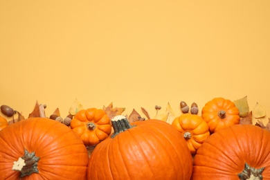 Photo of Flat lay composition with different ripe pumpkins and autumn leaves on yellow background. Space for text