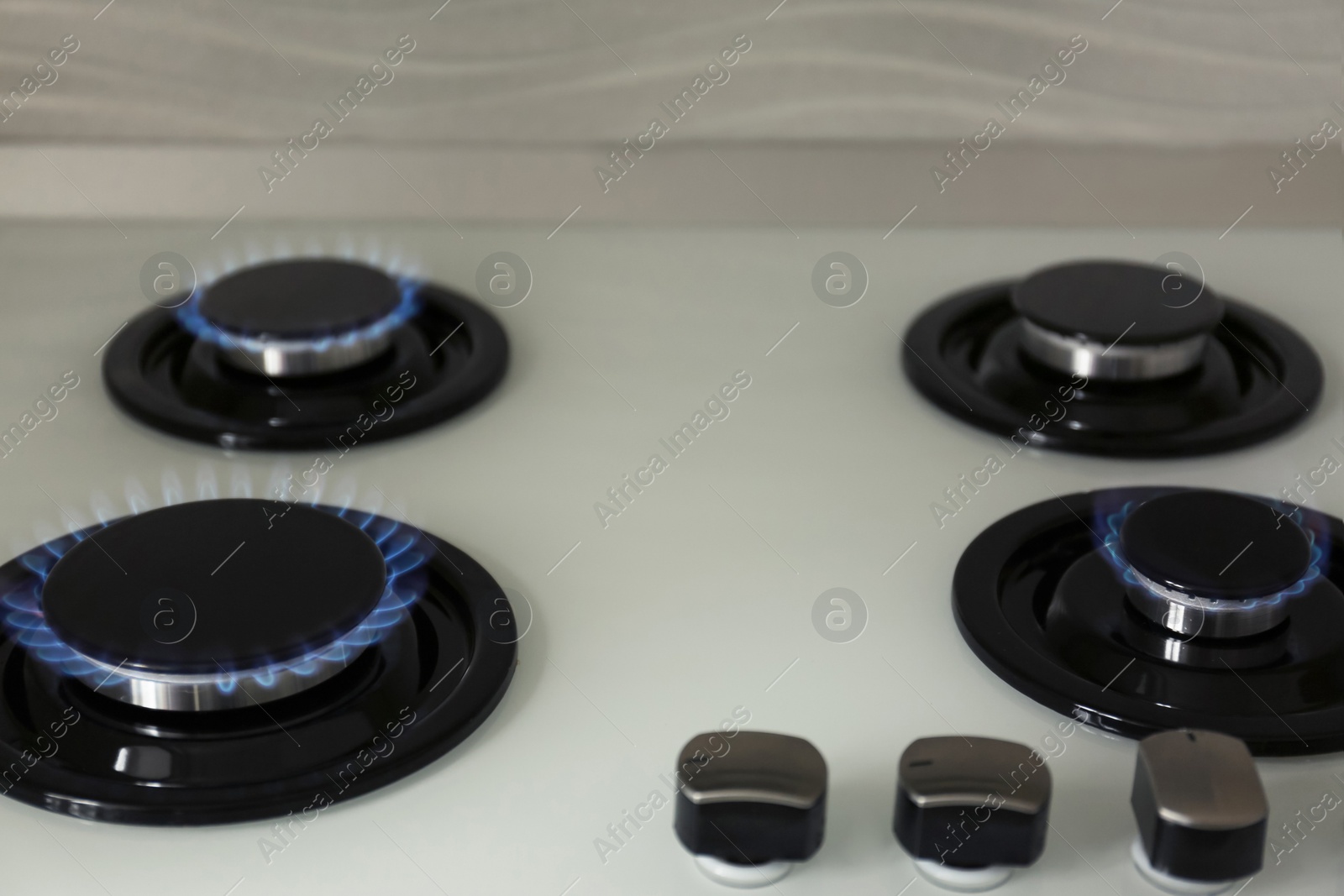 Photo of Gas burners with blue flame on modern stove