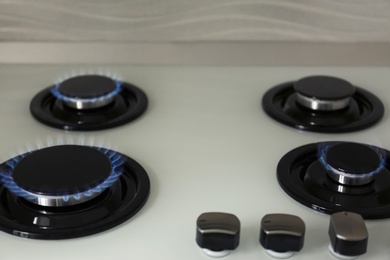 Photo of Gas burners with blue flame on modern stove