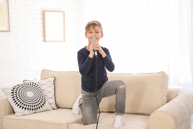 Photo of Cute boy with microphone on sofa in living room