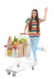 Young woman with full shopping cart on white background