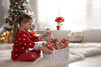 Photo of Cute little girl taking gift from Christmas advent calendar at home, space for text