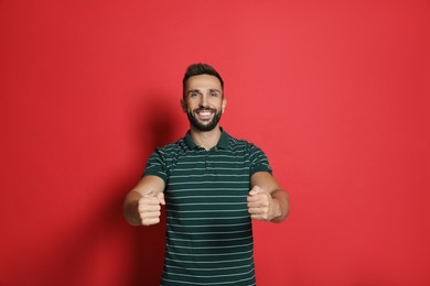 Photo of Happy man pretending to drive car on red background