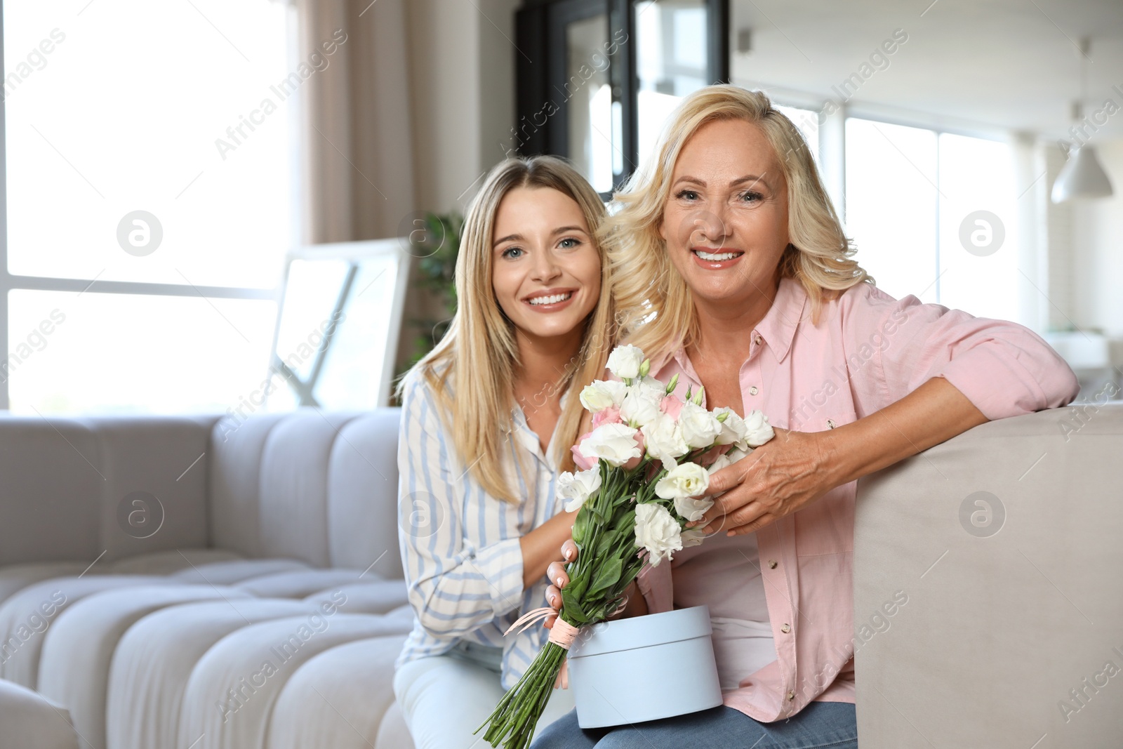 Photo of Young woman congratulating her mother in living room