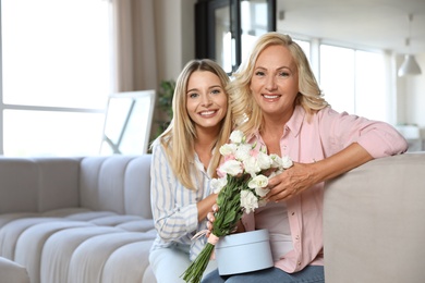 Young woman congratulating her mother in living room