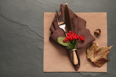 Autumn table setting. Cutlery, napkins, viburnum berries and leaf on grey textured background, top view with space for text