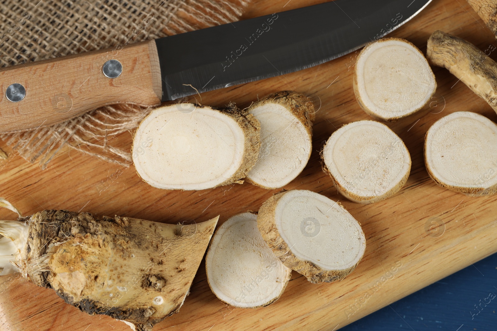 Photo of Board with cut horseradish root and knife on table, top view