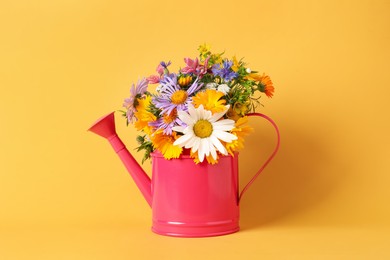 Pink watering can with beautiful flowers on yellow background