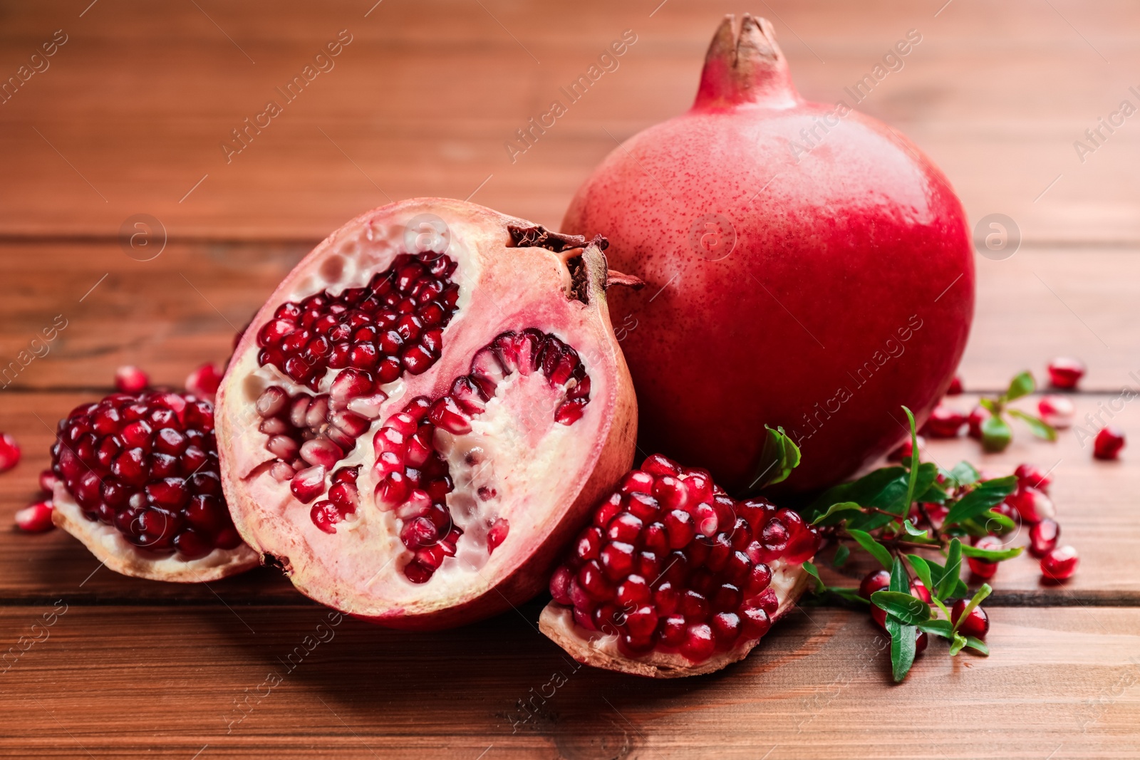 Photo of Delicious fresh ripe pomegranates on wooden table