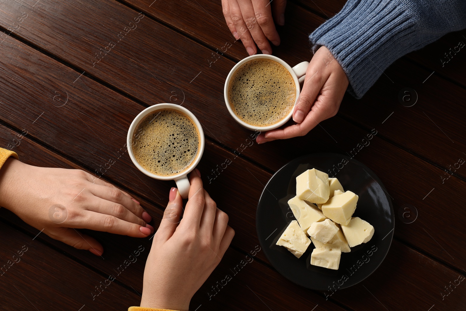 Photo of Women having coffee break at wooden table, top view