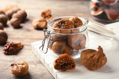 Photo of Jar with delicious dried figs on wooden board. Organic snack