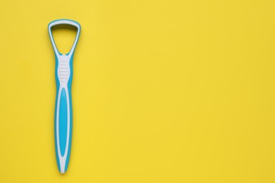 Photo of Light blue tongue cleaner on yellow background, top view. Space for text