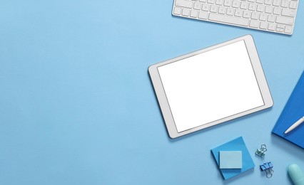 Photo of Modern tablet, stationery and keyboard on light blue background, flat lay. Space for text
