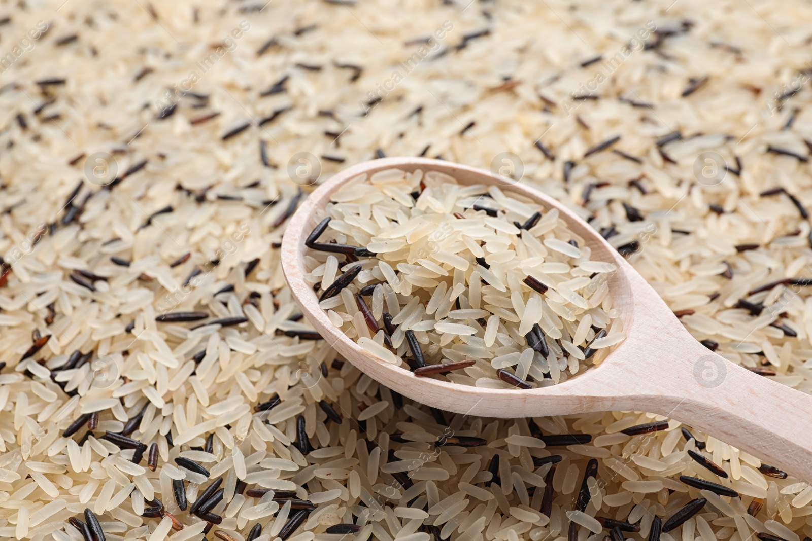 Photo of Mix of brown and polished rice with wooden spoon, closeup