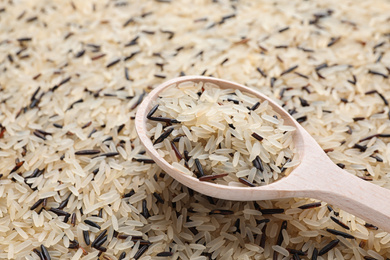 Photo of Mix of brown and polished rice with wooden spoon, closeup