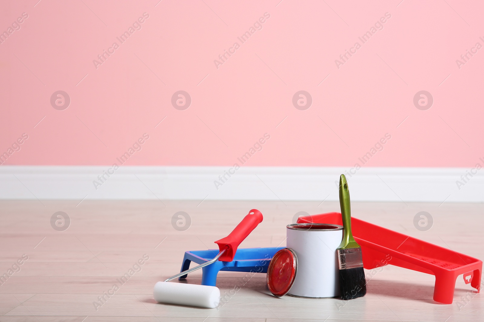 Photo of Can of paint and decorator tools on wooden floor indoors. Space for text