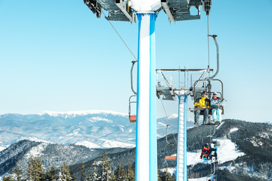 People using chairlift at mountain ski resort. Winter vacation