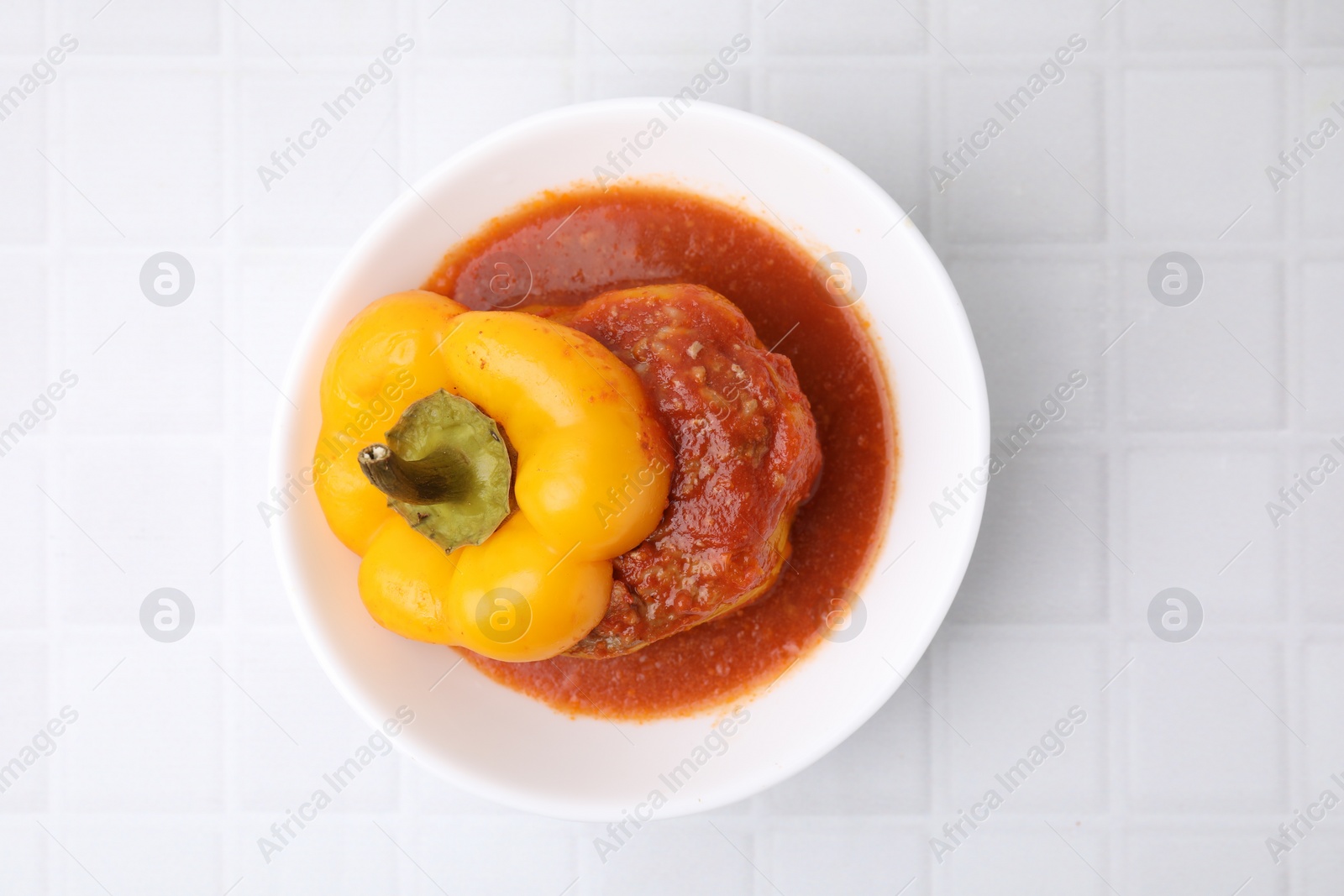 Photo of Delicious stuffed bell pepper on white tiled table, top view