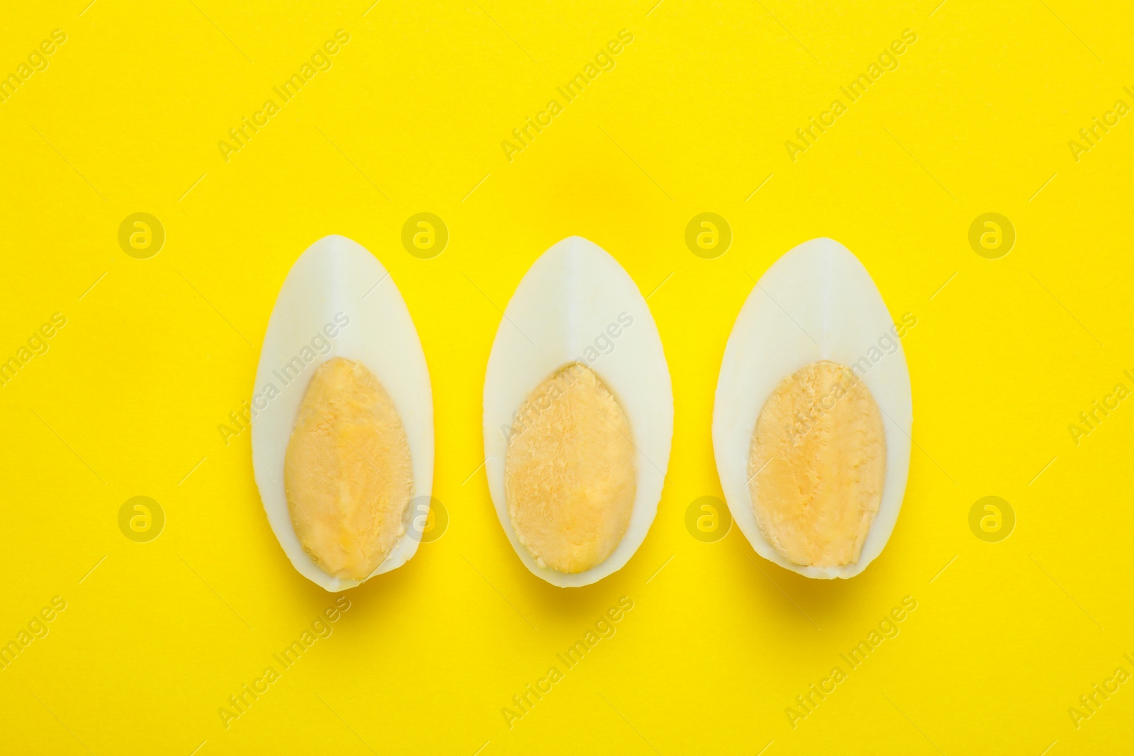 Photo of Slices of fresh hard boiled egg on yellow background, flat lay