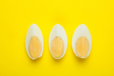 Photo of Slices of fresh hard boiled egg on yellow background, flat lay