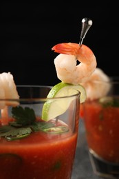 Tasty shrimp cocktail with sauce in glasses and lime on table against black background, closeup