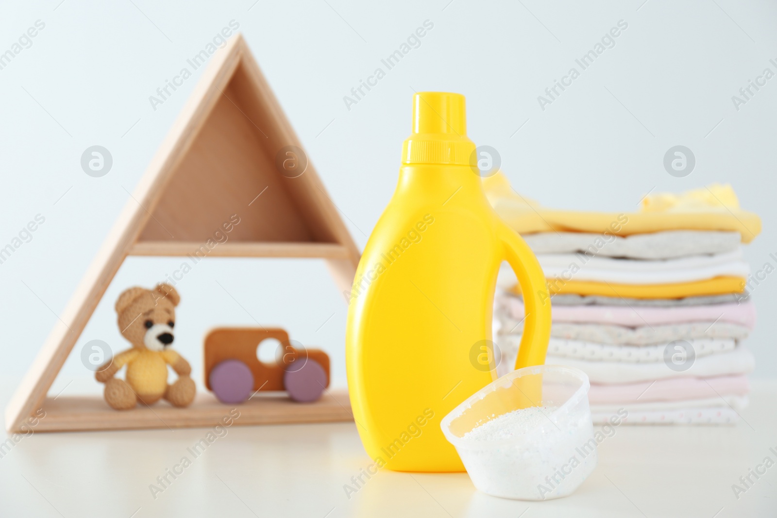 Photo of Detergent, toys and children's clothes on white table