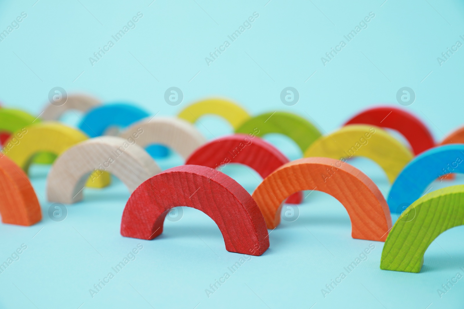 Photo of Colorful wooden pieces of playing set on light blue background. Educational toy for motor skills development