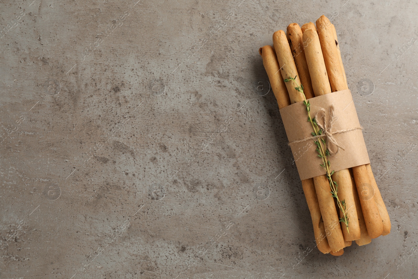Photo of Delicious grissini sticks with thyme on grey table, top view. Space for text