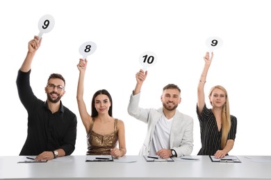 Panel of judges holding different score signs at table on white background