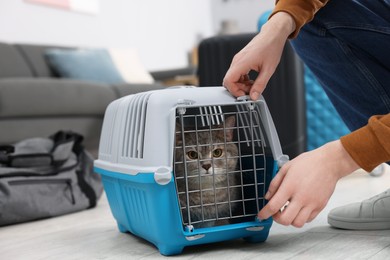 Photo of Travel with pet. Man closing carrier with cat at home, closeup