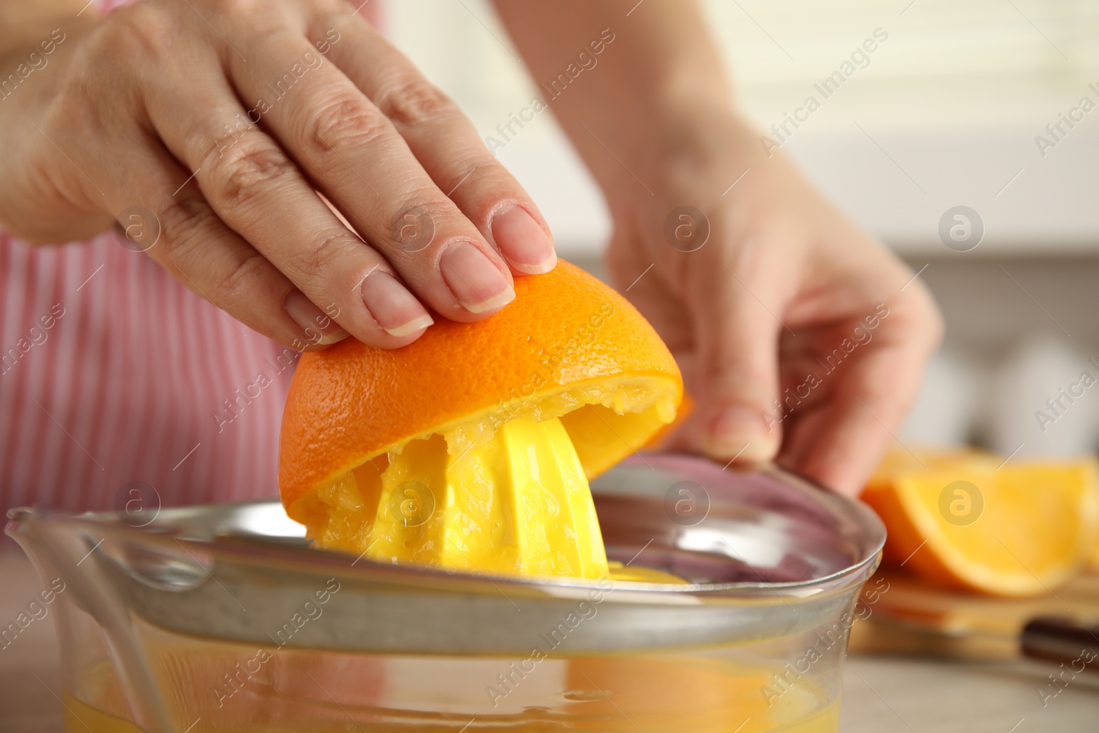 Photo of Woman squeezing orange juice at table, closeup