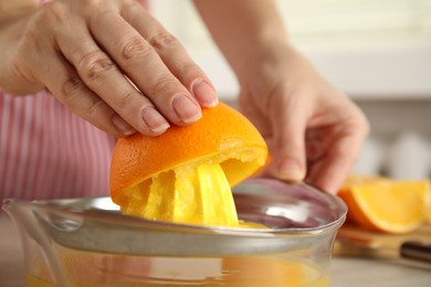 Photo of Woman squeezing orange juice at table, closeup