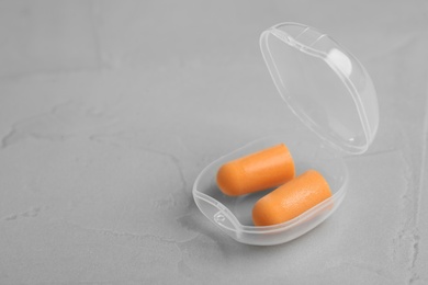 Photo of Pair of orange ear plugs in case on grey background. Space for text