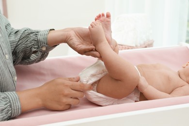 Mother changing her baby's diaper on table at home, closeup