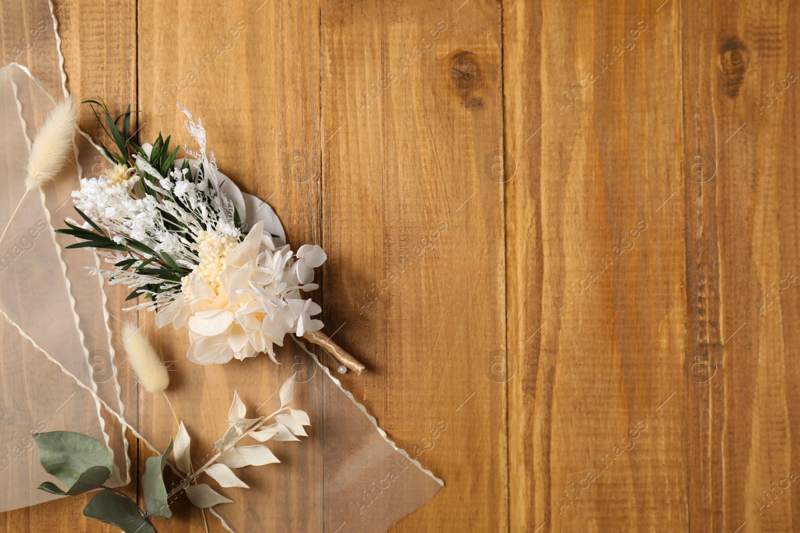 Photo of Stylish boutonniere and ribbon on wooden table, top view. Space for text