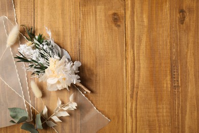 Photo of Stylish boutonniere and ribbon on wooden table, top view. Space for text